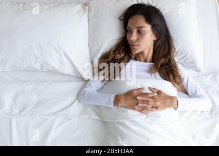 Jeune femme pensive posée seule dans la pensée de lit Banque D'Images