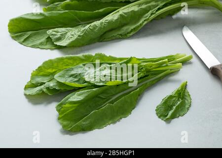 Bande de feuilles d'amsoi frais brutes sur une planche à découper Banque D'Images