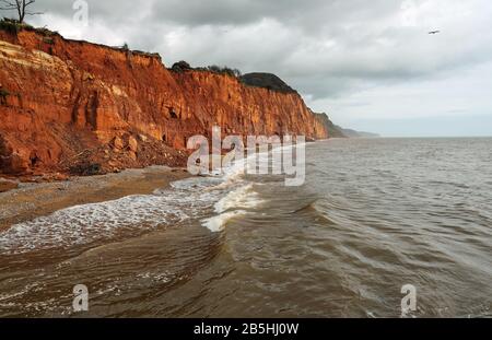 Les vagues se précipitent sous les falaises effondrées de Salcombe Hill à l'est de Sidmouth. La roche rouge sur les falaises est de la période Trias Banque D'Images