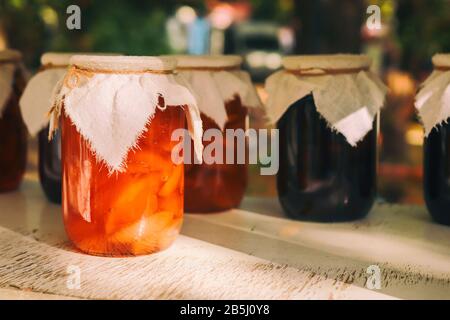 Des bocaux de fruits faits maison sont à la confiture sur une table en bois. Abricots en conserve faits maison dans un bocaux et abricots doux sur une table en bois sur fond sombre. Abricots frais Banque D'Images