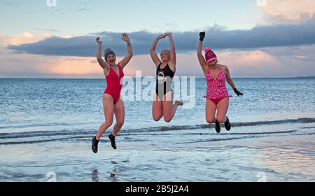 Portobello, Édimbourg, Écosse, Royaume-Uni, 8 mars 2020. Lors de la Journée internationale de la femme, une célébration de womenhod, en prenant une baignade au coucher du soleil organisée par WanderWomen. Photo de gauche à droite Dawn, Ali et Claire. Banque D'Images