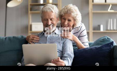 Un couple heureux d'âge moyen se détendre à la maison en utilisant un ordinateur portable Banque D'Images