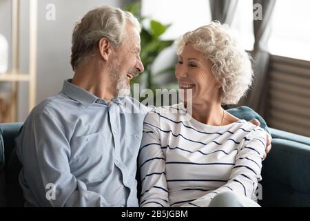 Couple d'âge mûr souriant se détendre à la maison embrassant Banque D'Images