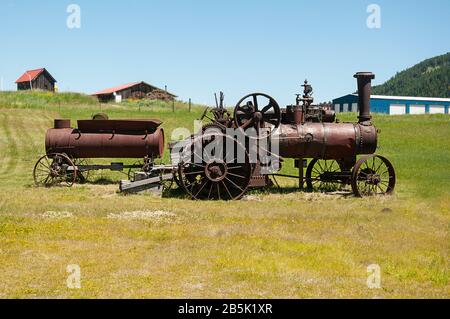 Machines anciennes de tracteurs de ferme qui est rouillée avec d'autres équipements de ferme qui sont des antiquités. Sur les terres agricoles rurales avec le ciel bleu dans cette image agricole Banque D'Images