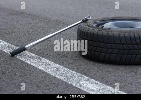 Une roue et un tournevis à pneu plat se trouvent sur une route en asphalte. Service automobile. Concept de remplacement des pneus, Prague, mars 2020 Banque D'Images