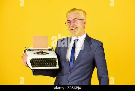 Objets anciens du vendeur. Connaisseur des valeurs vintage. Machine à écrire vintage. Les vieux habitudes de l'auteur de bâton. Les hommes d'affaires utilisent la technologie rétro. Homme mûr teint les cheveux de barbe fond jaune. Magasin de marchandises d'occasion. Banque D'Images