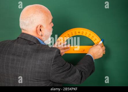 l'enseignant de l'homme senior utilise l'outil de procréation. l'homme tuteur barbu tire avec le dirigeant sur le tableau noir. retour à l'école. sujet et disciplines favoris. Éducation et concept scolaire. Apprentissage à la maison. Banque D'Images