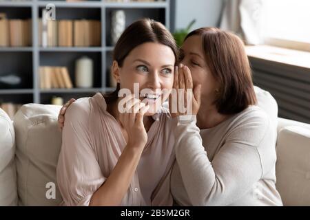 Mère mûre racontant des rumeurs à curieuse surprise grognup fille. Banque D'Images