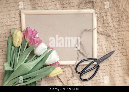 Plat de fleurs tulipes gros plan sur un cadre en bois, arrière-plan vintage, ciseaux fleuristes, minimalisme. Concept de vacances de printemps Banque D'Images