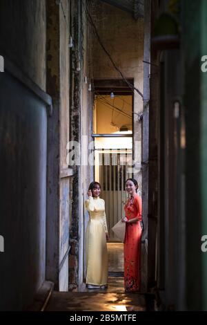 Deux jeunes femmes à Ao Dai s'habille dans un complexe de logements pauvres dans le vieux Saigon, au Vietnam Banque D'Images