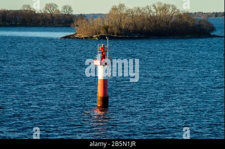 Phare dans le détroit entre les îles de l'archipel de Stockholm, éclairé par les rayons du soleil, en début de matinée. Banque D'Images