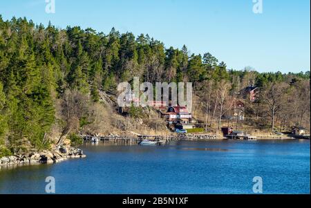 Des maisons d'été pittoresques peintes en rouge falun traditionnel sur l'île de l'archipel de Stockholm dans la mer Baltique en début de matinée. Banque D'Images