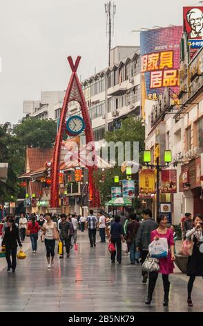 Guilin, Chine - 9 mai 2010 : rue commerçante piétonne de Zhengyang. Tour d'horloge sous le ciel pluvieux avec beaucoup de clients présents. Lumières et publicité colorée Banque D'Images