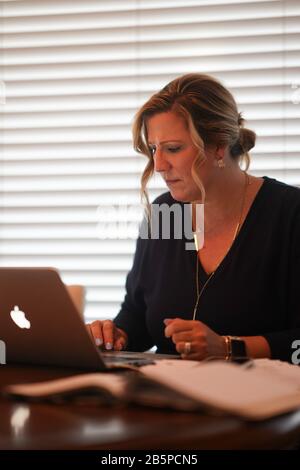 Une femme exerce des activités tout en utilisant un ordinateur portable. Banque D'Images