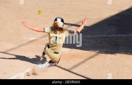 Un joueur de baseball Glisse Dans la base de maison Pendant que le ballon est en vol À Travers l'air Banque D'Images
