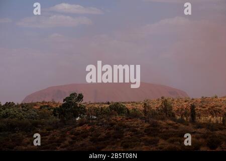 Tempête de poussière du désert obscurcissant la vue sur le massif rocher de grès d'Uluru dans le paysage de Yulara Banque D'Images