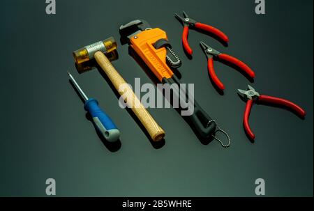 Jeu d'outils mécaniques isolés sur fond noir. Tournevis, pince coupante d'extrémité rouge, pince de blocage, pinces, marteau en plastique avec poignée en bois Banque D'Images
