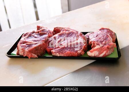Plateau de steaks de mandrin frais coupés sur un comptoir dans une boucherie ou un restaurant avec un espace de copie ci-dessous Banque D'Images