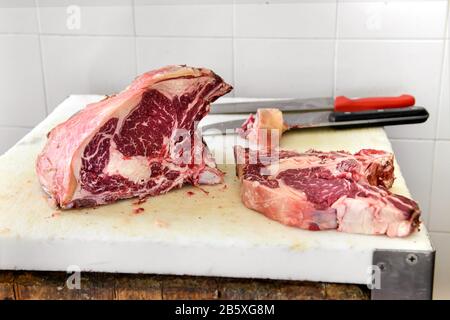 Tranche de bifteck de côtes sur la planche à découper des bouchers avec deux couteaux en gros plan dans une boucherie Banque D'Images