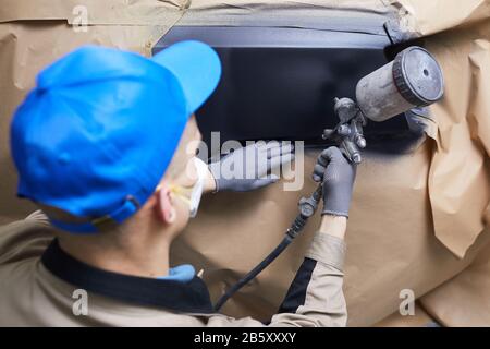 Vue arrière horizontale de gros plan prise de vue de l'homme non reconnaissable sur une surface de carrosserie de voiture de peinture uniforme Banque D'Images