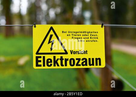 Panneau d'avertissement jaune de clôture électrique avec texte allemand disant "Attention, clôture électrique" Banque D'Images