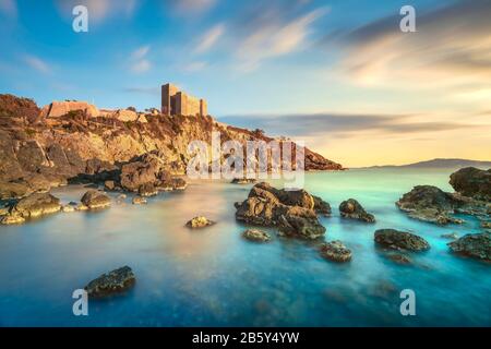 Plage rocheuse de Talamone et forteresse médiévale Rocca Aldobrandesca et murs au coucher du soleil. Maremma Argentario Italie destination de voyage. Toscane, Italie. Banque D'Images