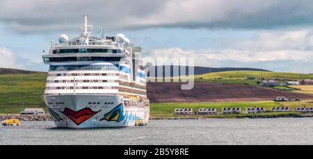 Le bateau de croisière allemand Aidabella, amarré au large de Lerwick, les tours Shetland au-dessus des maisons voisines sur la rive. Exploité par AIDA Cruises, une partie de Carnival Corporation. Banque D'Images