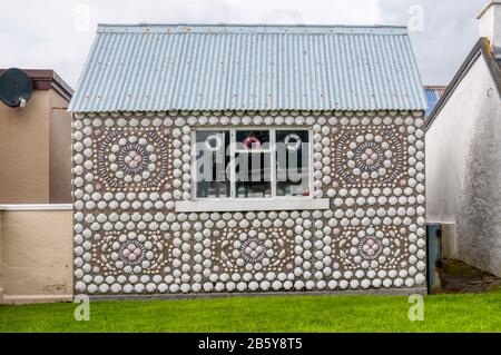 Un petit bâtiment couvert de coquillages à Hamnovoe sur l'île de Burra Ouest au large de la zone continentale de Shetland. Banque D'Images