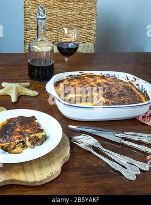 Greek Moussaka, un Célèbre plat d'aubergines grecques Maison, servi sur une assiette accompagnée d'un verre de vin rouge. Image De Stock. Banque D'Images