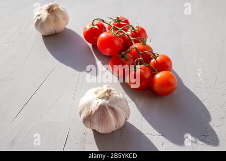 Tomates fraîches et ail sur fond gris. Ingrédients pour ketchup. Espace de copie. Banque D'Images
