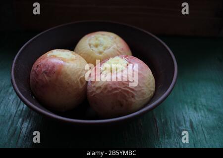 Pommes cuites au four farcies au fromage cottage dans un bol en céramique sur fond rustique en bois. Dessert aux fruits sains Banque D'Images