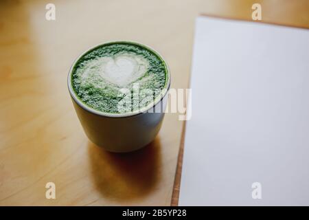 Une tasse de thé vert matcha bio sur un bureau en bois. Concept de négociation en lieu de travail commun. Concept de corail vivant Banque D'Images