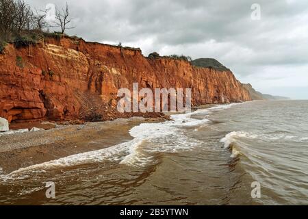 Les vagues se précipitent sous les falaises effondrées de Salcombe Hill à l'est de Sidmouth. La roche rouge sur les falaises est de la période Trias Banque D'Images