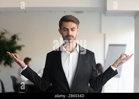 Jeune homme d'affaires conscient faisant des exercices de respiration de yoga. Banque D'Images