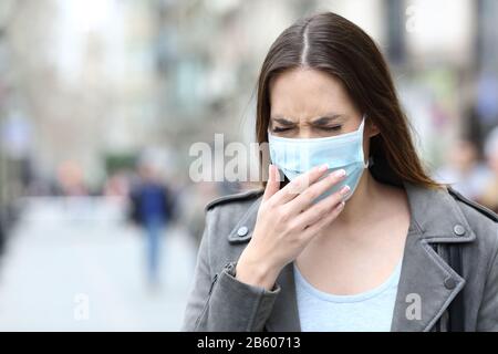 Portrait d'une femme malade avec masque médical de protection toussant sur la rue de la ville Banque D'Images