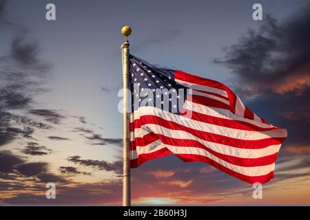 Un drapeau américain sur le flagpole se foulant dans le vent sous un ciel bleu clair Banque D'Images