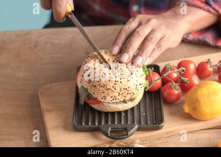 Le chef du maître d'hôtel utilise un hamburger à coupe de couteau fait maison dans la cuisine. Banque D'Images