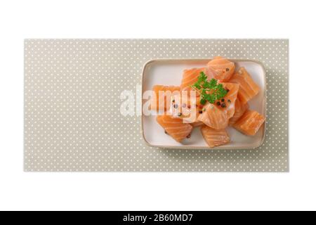filet de saumon cru sur fond blanc, poisson cru, poivre et herbes aromatiques Banque D'Images