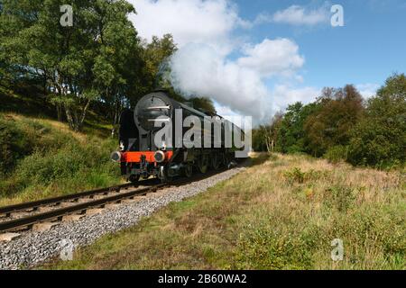 Un train à vapeur vintage traverse les Maures de North York avec de la vapeur intense lors d'une matinée d'automne près de Goathland, Yorkshire, Royaume-Uni. Banque D'Images