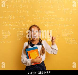 Jeune étudiant est avec une expression choquée et indique une formule complexe. Fond jaune Banque D'Images