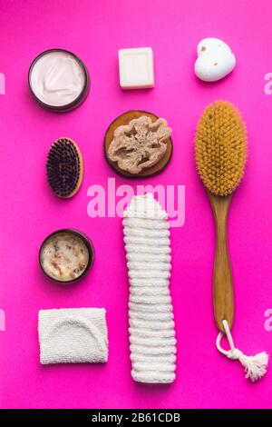 Gommage, lotion, savons, serviette en coton, gant exfoliant pour le soin du corps sur fond rose. Kit spa écologique, plat Banque D'Images