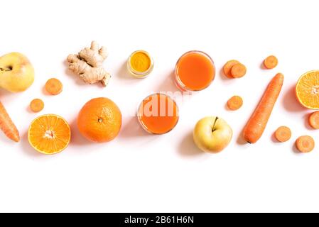 Boisson Detox cleanse, orange smoothie aux fruits et légumes ingrédients. Dans des verres à jus biologiques. Carotte, pomme, gingembre, poudre de curcuma et orange mix Banque D'Images