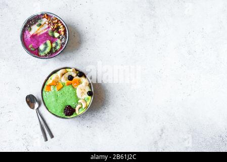 Smoothie Bowls colorés pour un petit-déjeuner sain, vue de dessus, espace de copie. Bols à smoothie aux épinards et aux baies verts avec divers garnitures. Mousse végétalienne brute Banque D'Images