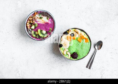Smoothie Bowls colorés pour un petit-déjeuner sain, vue de dessus, espace de copie. Bols à smoothie aux épinards et aux baies verts avec divers garnitures. Mousse végétalienne brute Banque D'Images