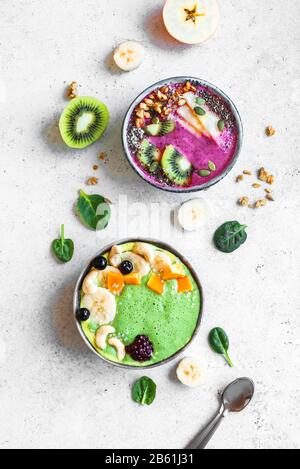 Smoothie Bowls colorés pour un petit-déjeuner sain, vue de dessus, espace de copie. Bols à smoothie aux épinards et aux baies verts avec divers garnitures. Mousse végétalienne brute Banque D'Images