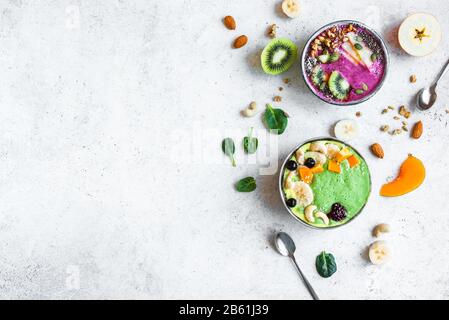 Smoothie Bowls colorés pour un petit-déjeuner sain, vue de dessus, espace de copie. Bols à smoothie aux épinards et aux baies verts avec divers garnitures. Mousse végétalienne brute Banque D'Images