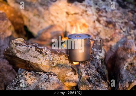 Un mug près d'un feu de camping lors d'un voyage de randonnée Banque D'Images