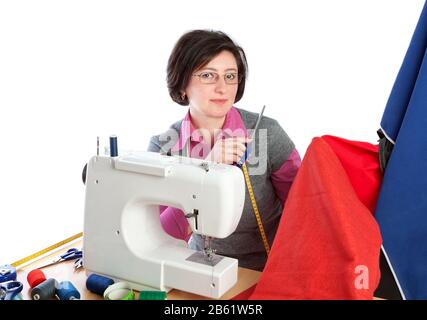 Femme d'âge moyen tenant une paire de ciseaux à la machine à coudre. Sur fond blanc. Banque D'Images
