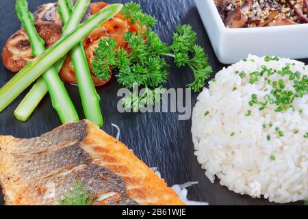 Un délicieux morceau de poisson sur fond de légumes verts, de riz et de champignons. Plats à sushi. Banque D'Images