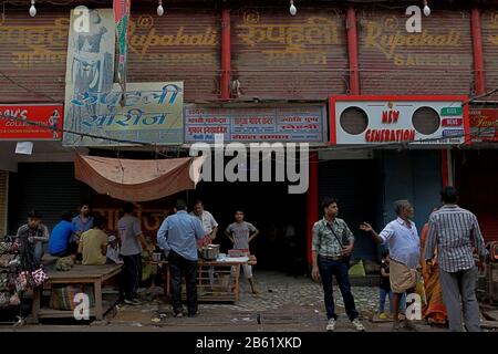 Les gens se rassemblent et s'entretient en face d'un vendeur de nourriture de rue dans la zone commerçante Varanasi. Varanasi City, Uttar Pradesh, Inde. Banque D'Images